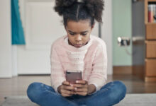 Une petite fille jouant avec son smartphone.