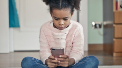 Une petite fille jouant avec son smartphone.
